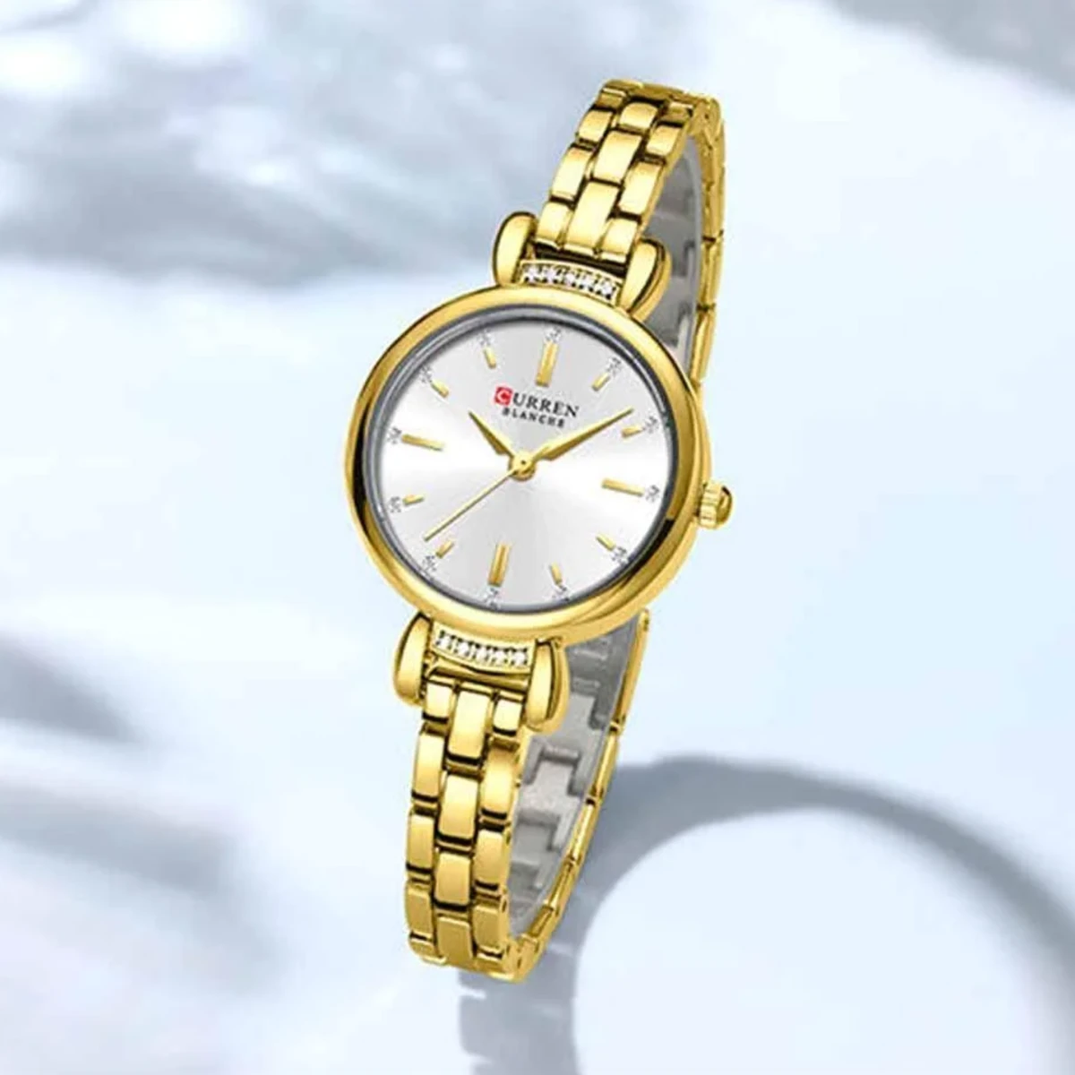 rewak-hd-7057 Montre Femme CURREN 9098 – Dorée, Cadran Blanc et Attaches Serties de Cristaux